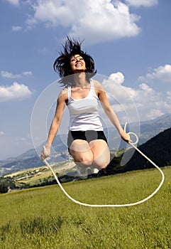 Jumping rope attractive women in meadow