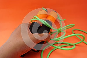 Jumping rope isolated on an orange background. Fitness and gym concept. Banners for websites, news. Green jump rope for exercise