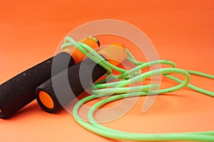 Jumping rope isolated on an orange background. Fitness and gym concept. Banners for websites, news. Green jump rope for exercise