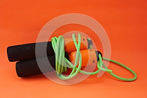 Jumping rope isolated on an orange background. Fitness and gym concept. Banners for websites, news. Green jump rope for exercise