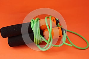 Jumping rope isolated on an orange background. Fitness and gym concept. Banners for websites, news. Green jump rope for exercise