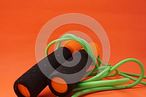 Jumping rope  on an orange background. Fitness and gym concept. Banners for websites, news. Green jump rope for exercise