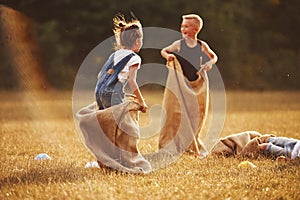 Jumping sack race outdoors in the field. Kids have fun at sunny daytime