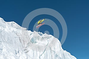 A jumping skier jumping from a glacier against a blue sky high in the mountains. Professional skiing