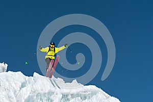 A jumping skier jumping from a glacier against a blue sky high in the mountains. Professional skiing