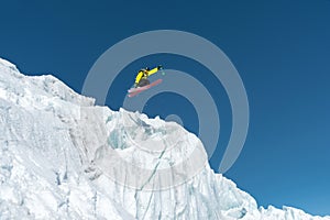 A jumping skier jumping from a glacier against a blue sky high in the mountains. Professional skiing