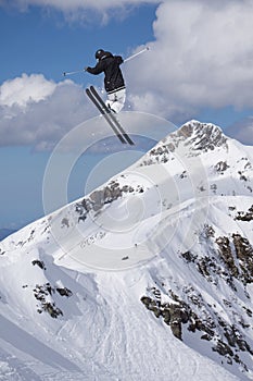 A jumping skier in the mountains. Mountain ski, winter extreme sport.