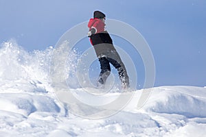 Jumping snowboarder from hill in winter