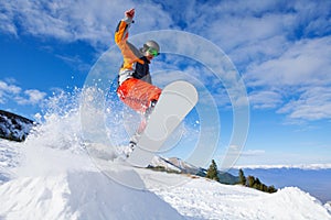 Jumping snowboarder from hill in winter