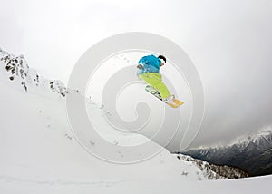 Jumping snowboarder in mountains