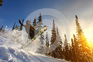 Jumping snowboarder on snowboard in mountains in ski resort