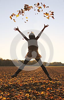 Jumping teenage girl, throwing leaves up in the air