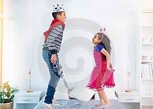 Jumping up for joy. two young children dressed up as superheroes jumping on a bed at home.