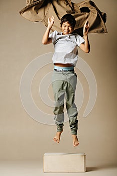 Jumping up from a pedestal indian boy throwig long sleeve shirt