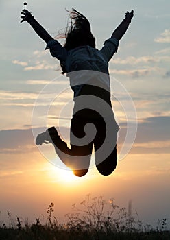 Jumping woman and sunset silhouett