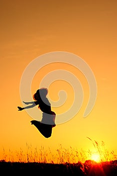 Jumping woman and sunset silhouette