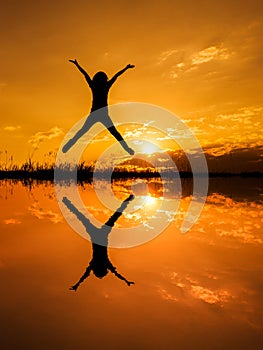 Jumping woman and sunset silhouette,water reflect