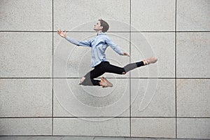 Jumping young buinessman in front of buildings, on the run in jump high