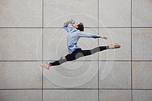 Jumping young buinessman in front of buildings, on the run in jump high