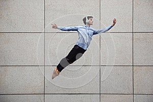 Jumping young buinessman in front of buildings, on the run in jump high