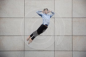 Jumping young buinessman in front of buildings, on the run in jump high