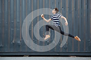 Jumping young buinessman in front of buildings, on the run in jump high