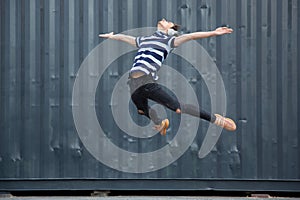 Jumping young buinessman in front of buildings, on the run in jump high