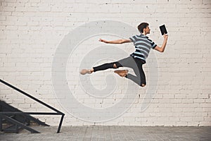 Jumping young buinessman in front of buildings, on the run in jump high