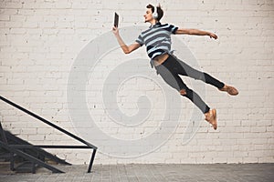 Jumping young buinessman in front of buildings, on the run in jump high