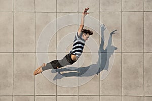 Jumping young buinessman in front of buildings, on the run in jump high