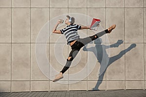 Jumping young buinessman in front of buildings, on the run in jump high