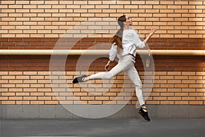 Jumping young woman in front of buildings, on the run in jump high