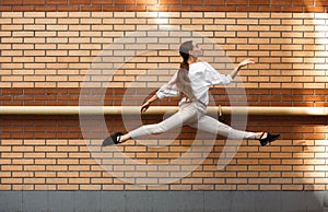 Jumping young woman in front of buildings, on the run in jump high