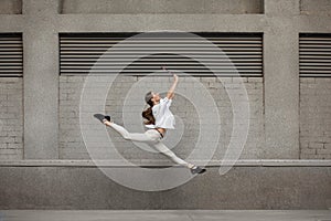 Jumping young woman in front of buildings, on the run in jump high