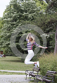 She jumps for joy in the futoski park Novi Sad and listens to music from headphones.