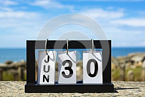 Jun 30 calendar date text on wooden frame with blurred background of ocean
