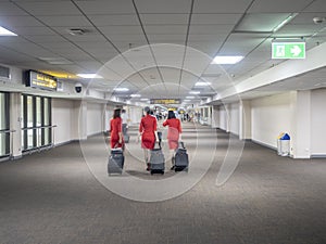 28 jun 20, Donmueng Airport, Bangkok, Thailand. Group of cabin crew in red uniform waking with trolley bag in empty terminal. Airp