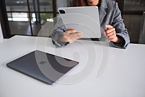 Jun 27th 2020 : A woman using Apple New Ipad Pro 2020 tablet pc with Apple MacBook Pro laptop computer on wooden table
