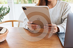 Jun 16th 2020 : A woman using Apple New Ipad Pro 2020 tablet pc with Apple MacBook Pro laptop computer on wooden table