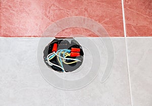 Junction box in wall with insulated wires and various adapters for sockets, internet, and branching of electrical wiring