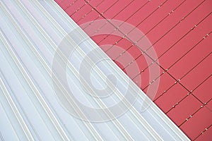 Junction of two textures: red metal rightangled tiles and white metal corrugated sheet