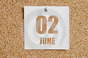 june 02. 02th day of the month, calendar date.White calendar sheet attached to brown cork board.Summer month, day of the