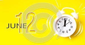 June 12nd. Day 12 of month, Calendar date. White alarm clock with calendar day on yellow background. Minimalistic concept of time
