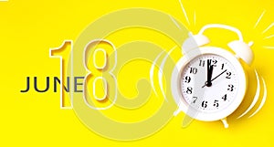 June 18th. Day 18 of month, Calendar date. White alarm clock with calendar day on yellow background. Minimalistic concept of time