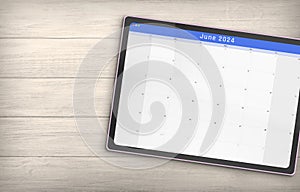 June 2024 Calendar on a Digital Tablet isolated on wood background with space for copy