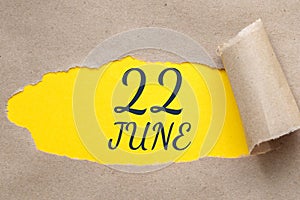 june 22. 22th day of the month, calendar date.Hole in paper with edges torn off. Yellow background is visible through