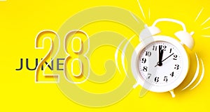 June 28th. Day 28 of month, Calendar date. White alarm clock with calendar day on yellow background. Minimalistic concept of time