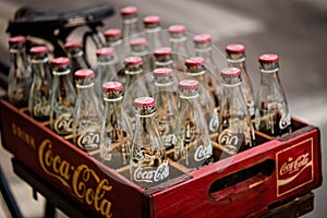 2020 June Bangkok Thailand. Vintage Coca-Cola clear glass bottle in Red Plastic Box carry on bicycle