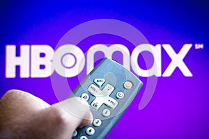 June 3, 2021, Brazil. In this photo illustration a person holds the TV remote control and in the background, the HBO Max logo