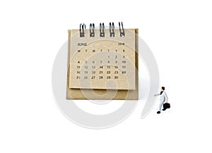 June. Calendar sheet and miniature plastic businessman on white